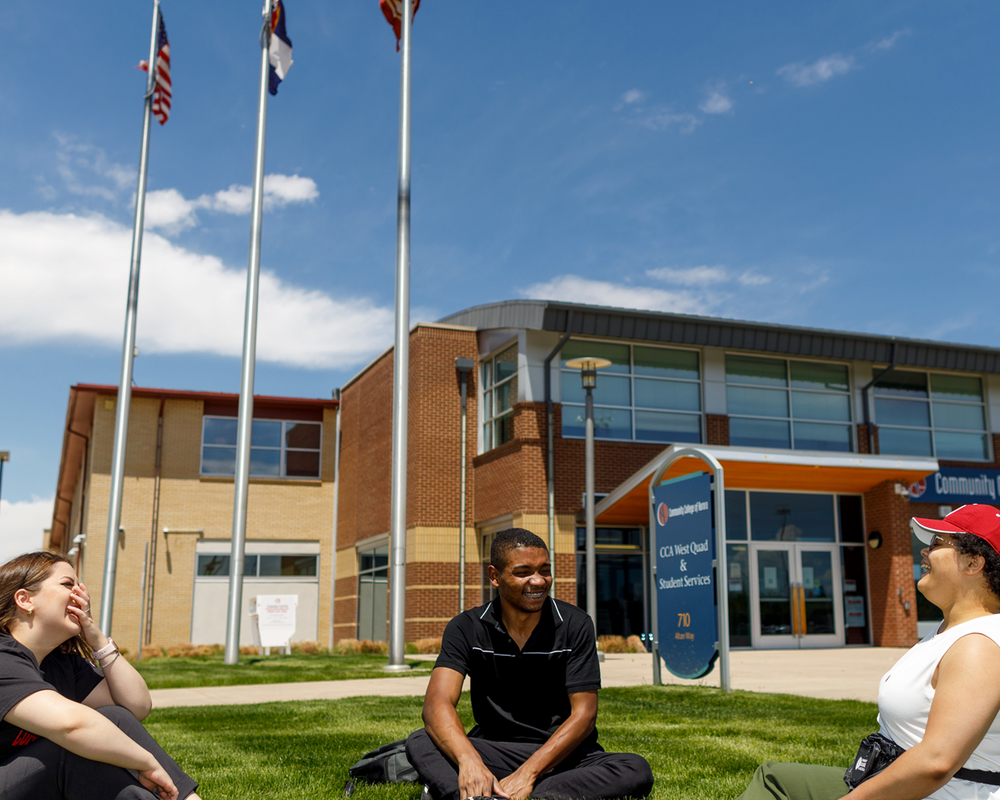 Photo of students sitting on grass in discussion at Community College of Aurora