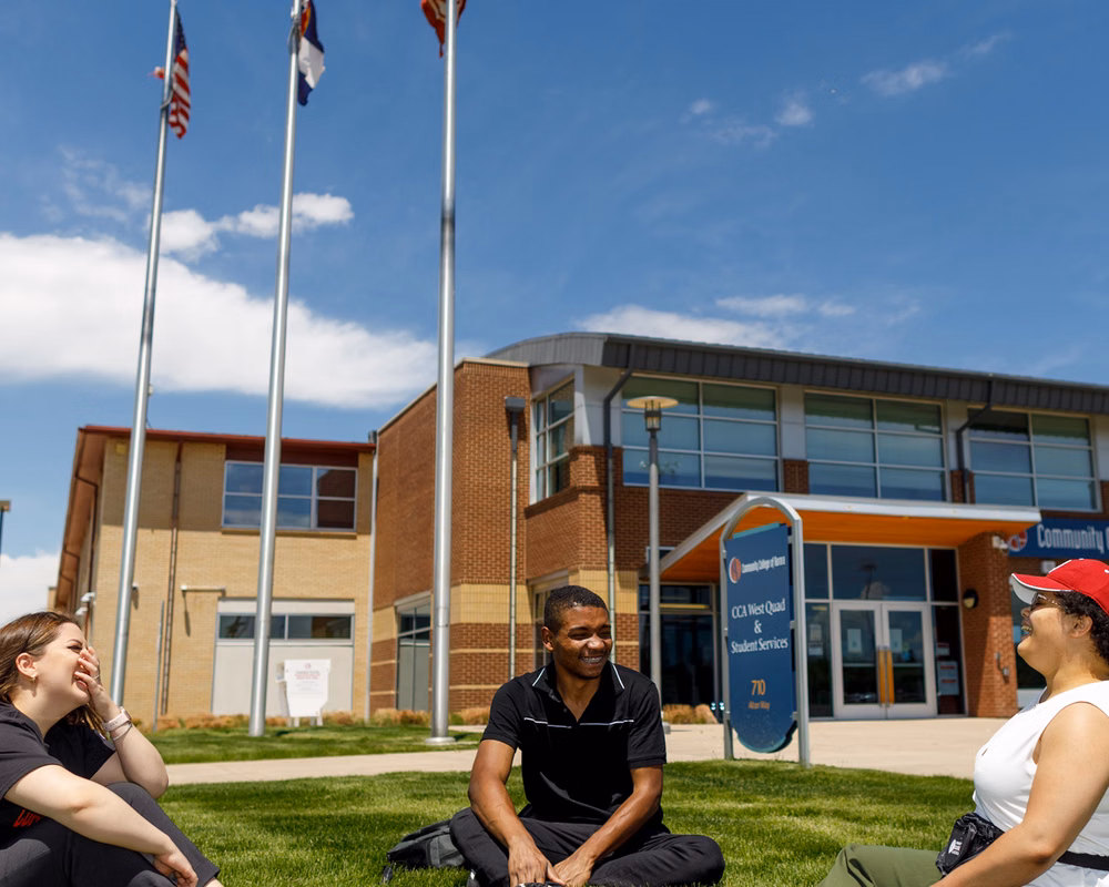 Photo of students sitting on grass in discussion at Community College of Aurora