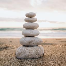 A cairn of smooth stones stacked on the sand symbolizes balance and tranquility by the sea