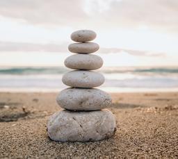 A cairn of smooth stones stacked on the sand symbolizes balance and tranquility by the sea