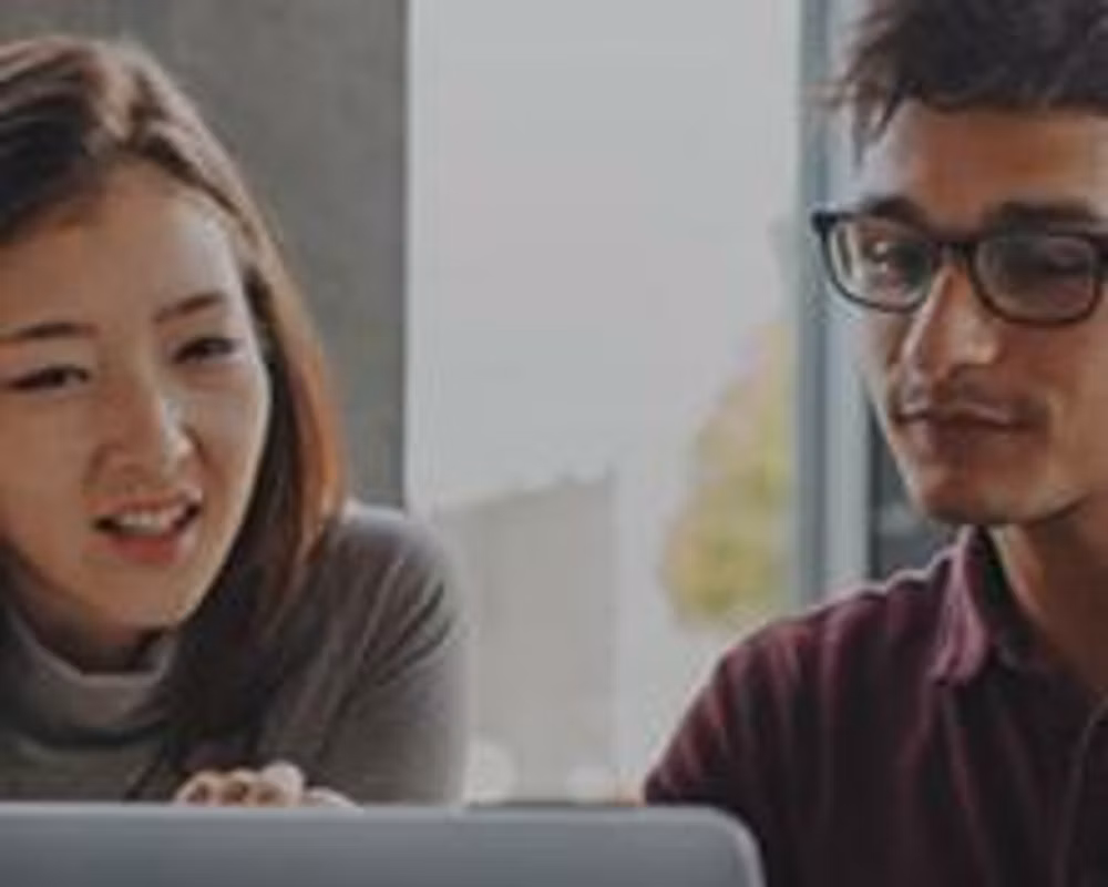 Two people collaborate over a laptop