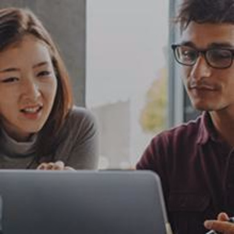 Two people collaborate over a laptop