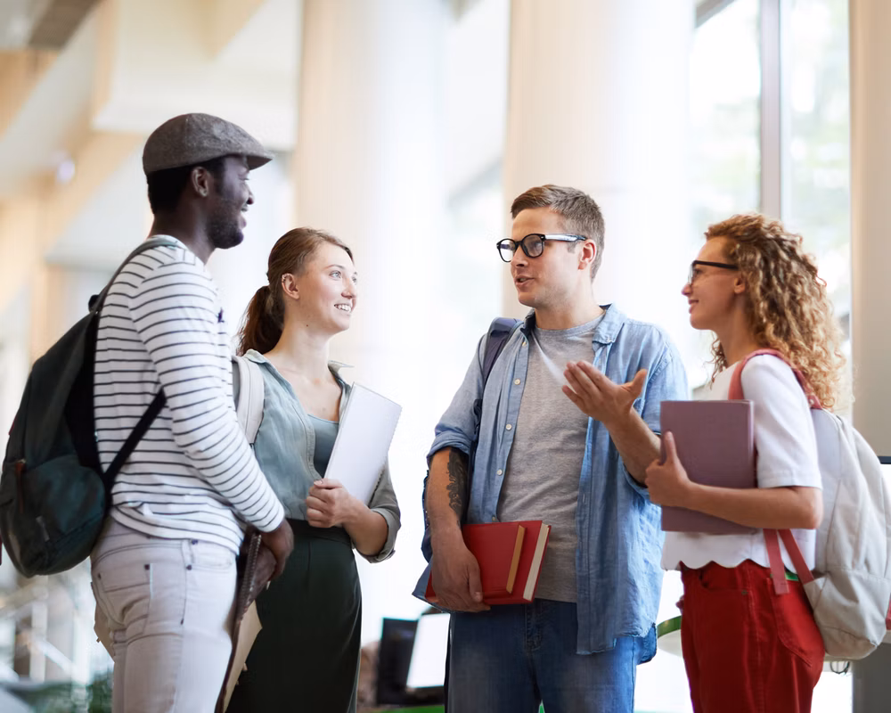 A diverse group of college students standing in a circle talking.