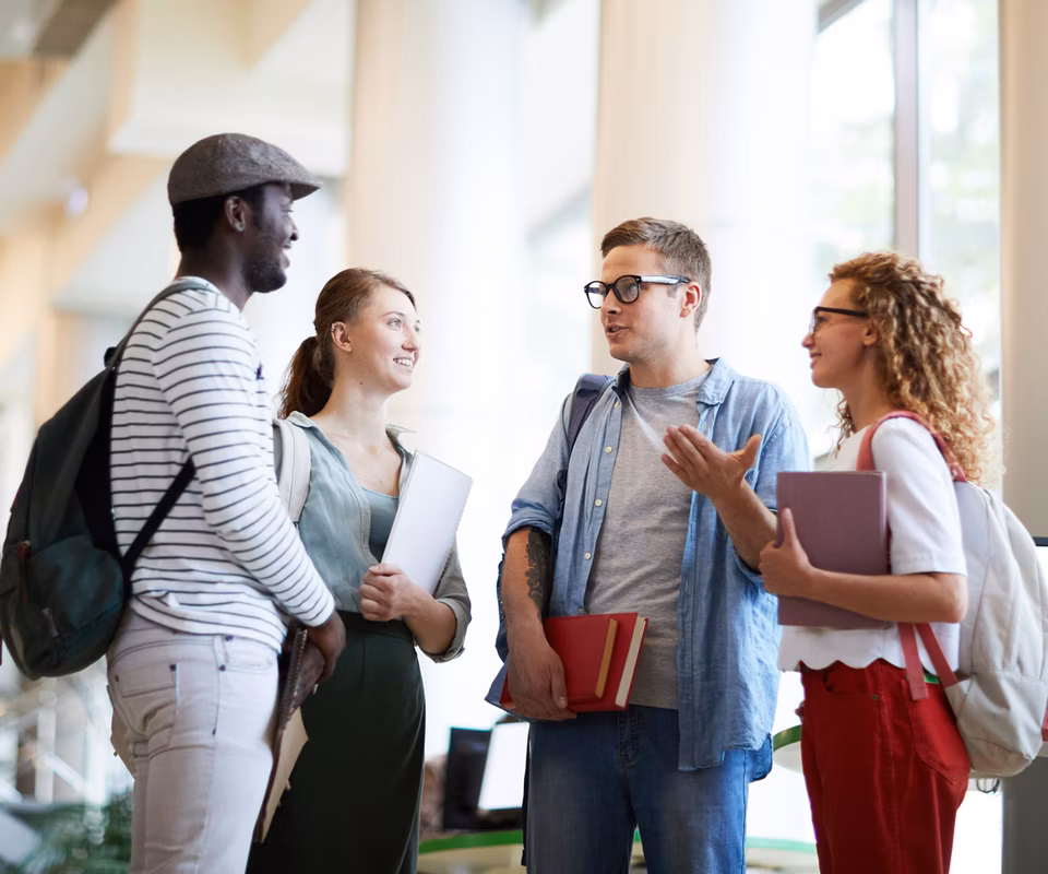 A diverse group of college students standing in a circle talking.
